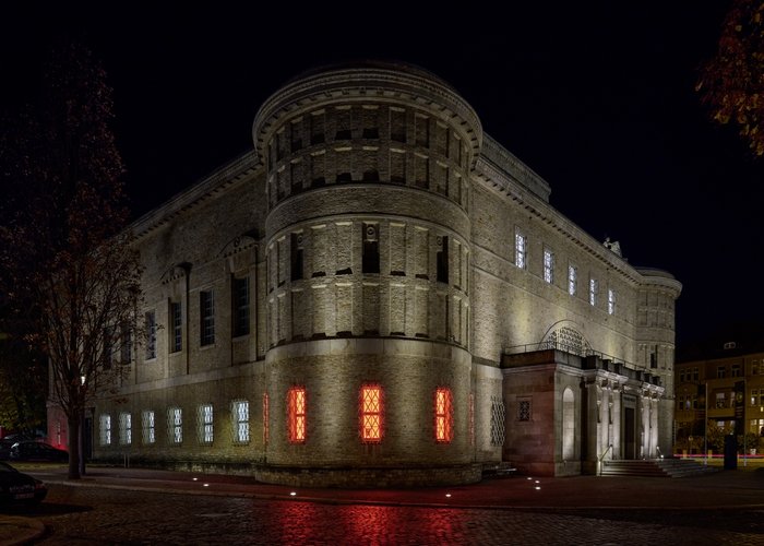 Wie ein Widerhall der brennenden Klöster des Frühlings 1525 erscheinen die feuerrot hinterleuchteten Fenster des Landesmuseums. Ganz wörtlich lässt der hallesche Künstler Klaus Pockrandt das Ausstellungsthema über das Museum hinausstrahlen. © Landesamt für Denkmalpflege und Archäologie Sachsen-Anhalt, Thomas Puttkammer.