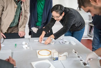 Vorsichtig nimmt Tomoko Emmerling einen in Seidenpapier eingeschlagenen Fund zur Begutachtung in die Hand. © Landesamt für Denkmalpflege und Archäologie Sachsen-Anhalt.