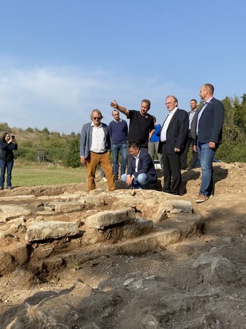 Direkt vor Ort: Grabungsleiter Prof. Dr. Felix Biermann präsentierte Ministerpräsident Dr. Reiner Haseloff am 18. September 2025 die Befundlage der Mallerbacher Kapelle. Im Vordergrund: Grundmauern der Apsis mit Resten des 1524 verbrannten Marienaltars. Von links: Prof. Dr. Harald Meller, Dr. Gerrit Deutschländer, Prof. Dr. Felix Biermann, Landrat André Schröder (hockend), Ministerpräsident Dr. Reiner Haseloff, Bürgermeister Daniel Kirchner (Allstedt). © Landesamt für Denkmalpflege und Archäologie Sachsen-Anhalt, Rouven Guder.