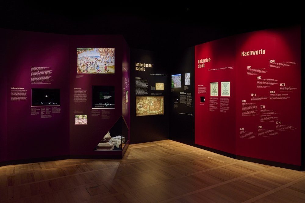 Blick in die Ausstellung: In einer Nische präsentiert die Ausstellung Einblicke in die aktuellen Forschungen an der Mallerbacher Kapelle (schwarz). © Landesamt für Denkmalpflege und Archäologie Sachsen-Anhalt, Thomas Puttkammer.