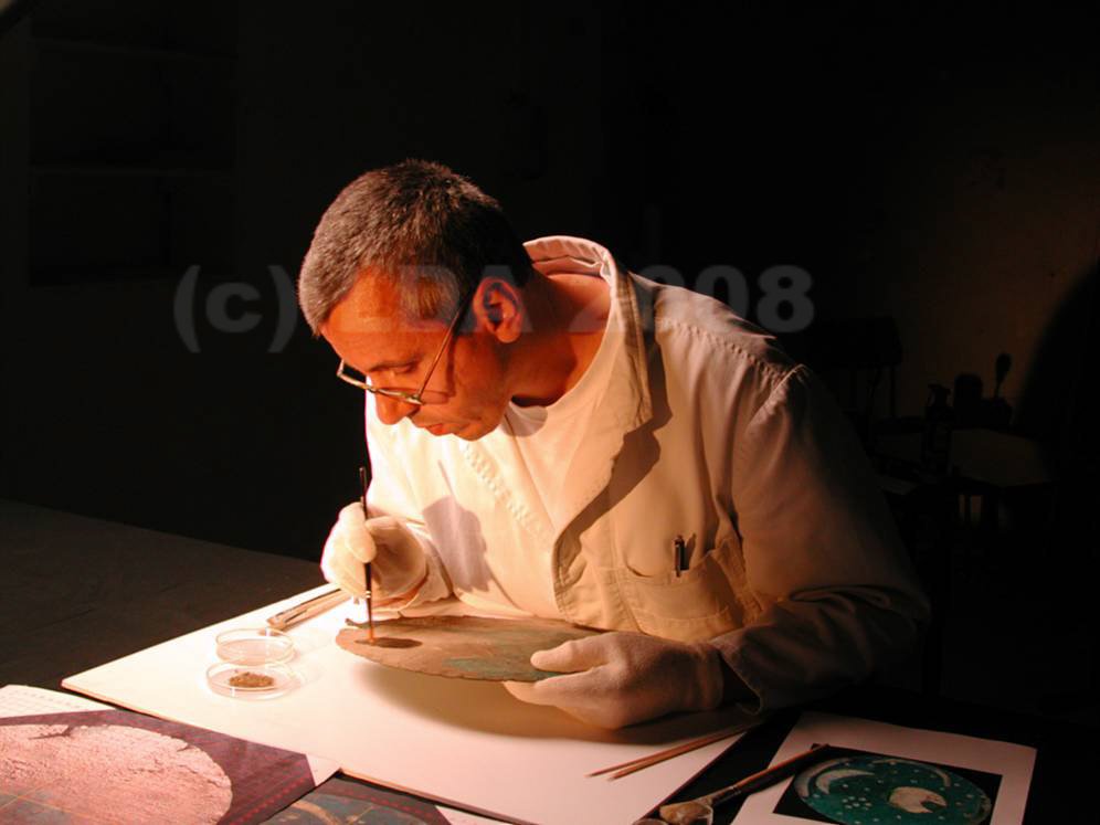 Restaurator Heiko Breuer entfernt Bodenanhaftungen von der Rückseite der Himmelsscheibe. © Landesamt für Denkmalpflege und Archäologie Sachsen-Anhalt.